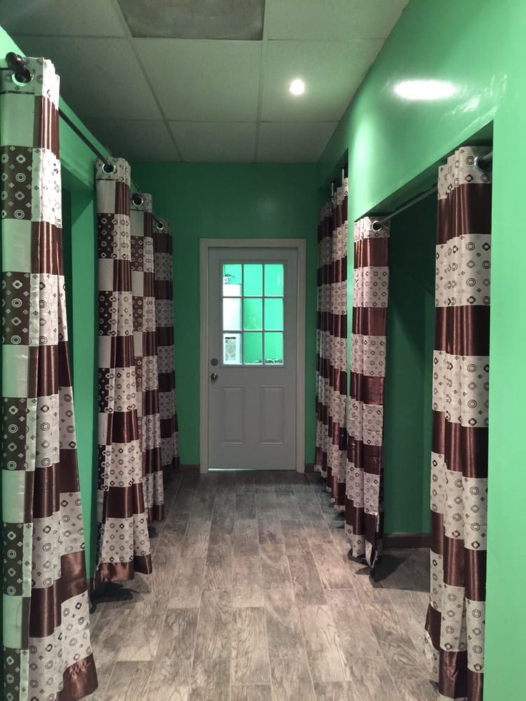 A hallway between curtained massage areas, patterned brown and cream curtains on both sides and a white door at the end.